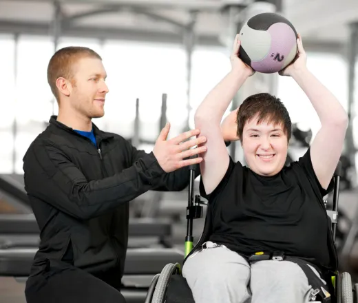 Person in wheelchair working out at the Y with a trainer